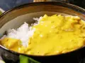 Miseczka białego ryżu polana gęstym, żółtym sosem masala.