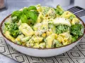 Sałatka z tortellini, brokułów, kukurydzy i jajka w kremowym sosie, udekorowana bazylią.