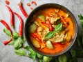 Miseczka czerwonego curry z mięsem, warzywami, papryczkami chili i bazylią.