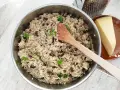 Kremowe risotto z pieczarkami i kurczakiem w garnku, obok kawałek parmezanu i tarka.