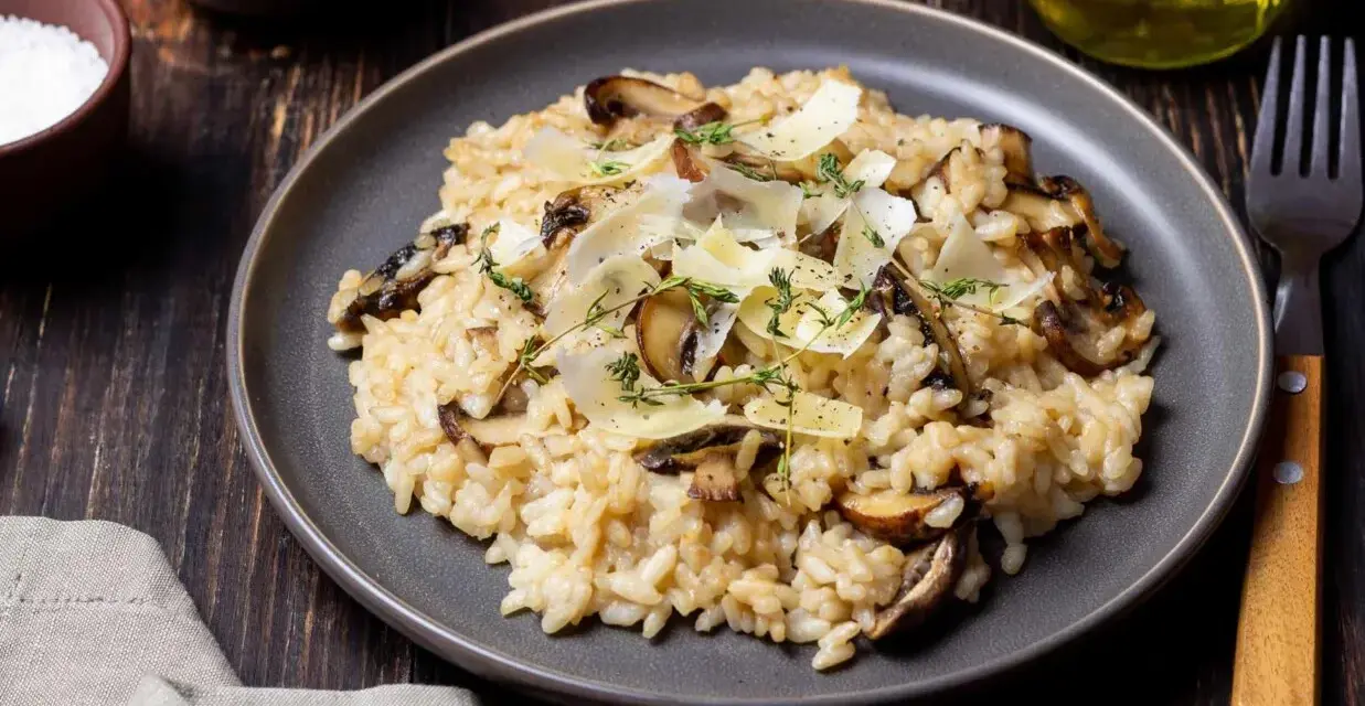 Kremowe risotto z pieczarkami, posypane parmezanem i ziołami.