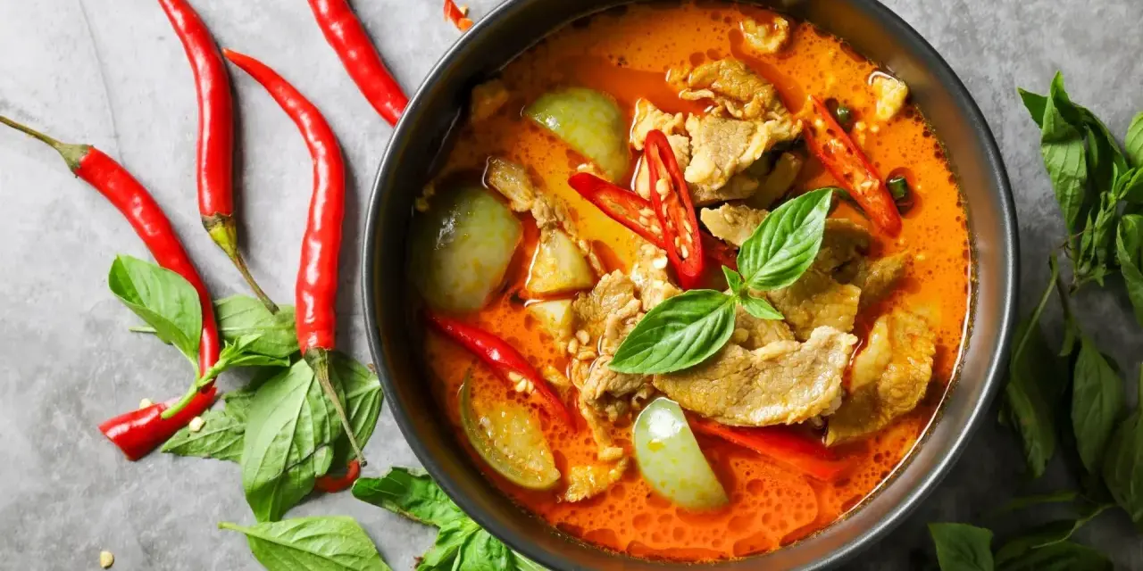 Miseczka czerwonego curry z mięsem, warzywami, papryczkami chili i bazylią.