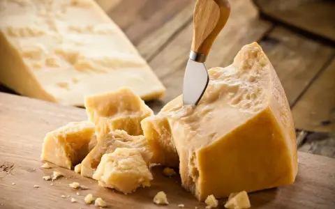Kawałki sera Grana Padano i Parmigiano Reggiano z nożem do sera.