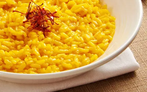 Miseczka kremowego risotto alla Milanese, ozdobiona nitkami szafranu.