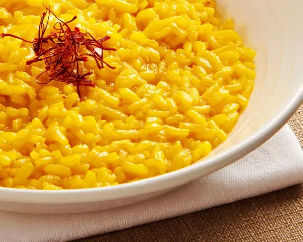 Miseczka kremowego risotto alla Milanese, ozdobiona nitkami szafranu.