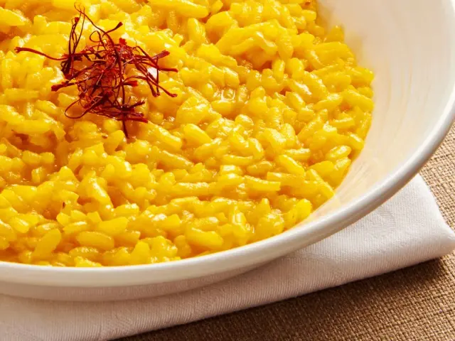 Miseczka kremowego risotto alla Milanese, ozdobiona nitkami szafranu.