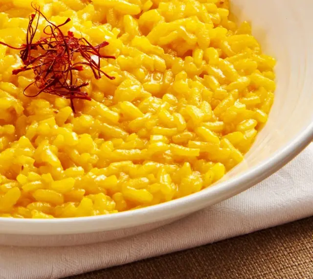 Miseczka kremowego risotto alla Milanese, ozdobiona nitkami szafranu.