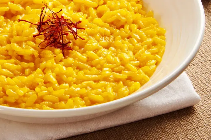 Miseczka kremowego risotto alla Milanese, ozdobiona nitkami szafranu.