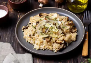 Kremowe risotto z pieczarkami, posypane parmezanem i ziołami.
