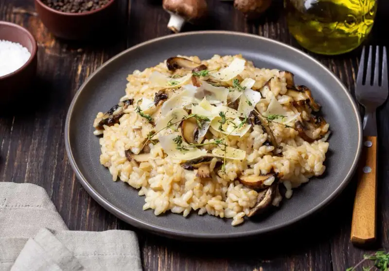 Kremowe risotto z pieczarkami, posypane parmezanem i ziołami.